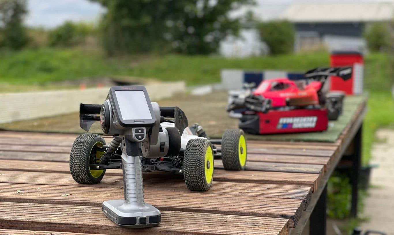 RC Auto Fernbedienung mit RC Auto im Hintergrund